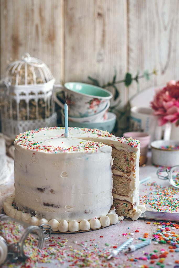 Tarta de cumpleaños feliz con confeti de colores y chocolate blanco.
